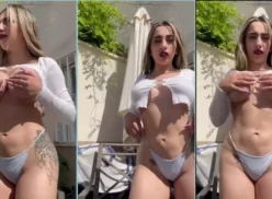 Una chica sin ropa aprieta sus grandes tetas en el jardín